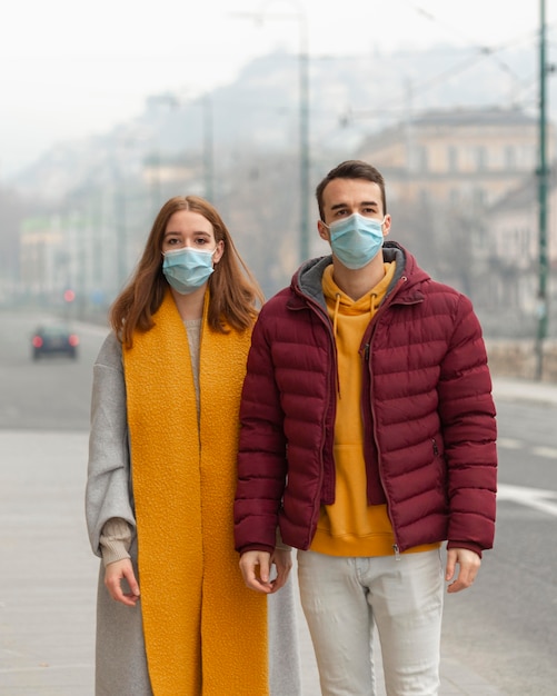 Foto grátis vista frontal de casal posando junto com máscaras médicas