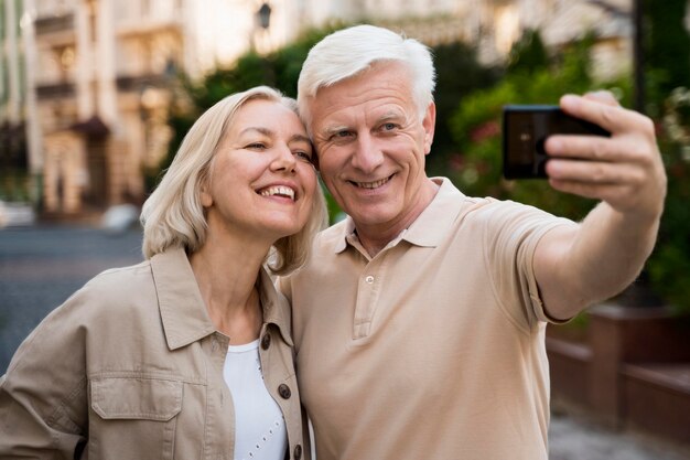 Vista frontal de casal sênior tirando uma selfie enquanto está na cidade