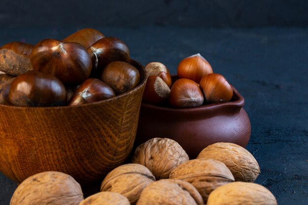 Vista frontal de castanhas com casca em um copo com avelãs com casca e nozes