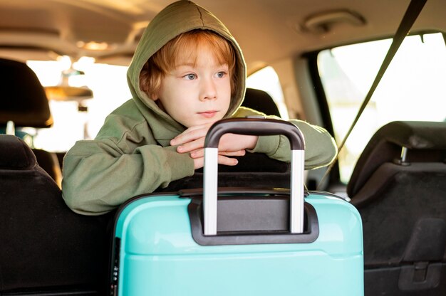 Vista frontal de criança com bagagem dentro do carro