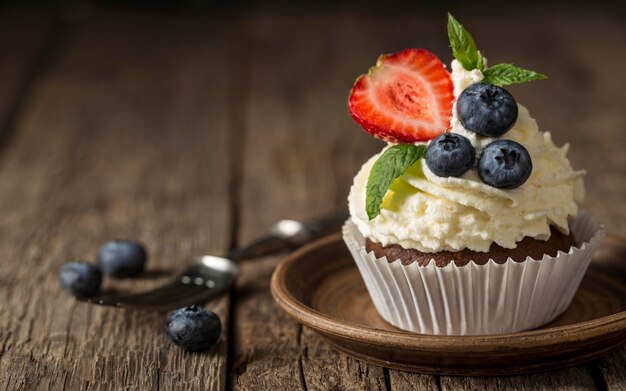 Vista frontal de cupcake saboroso com morango e mirtilo