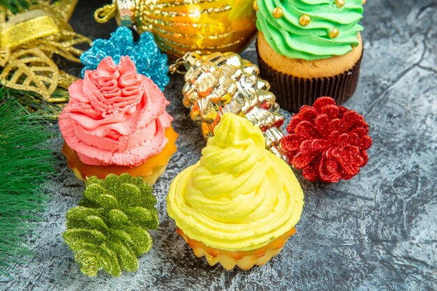Vista frontal de cupcakes coloridos e enfeites de natal em cinza