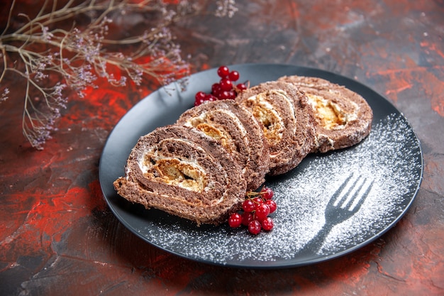 Vista frontal de deliciosos rolos de biscoito com frutas na superfície escura