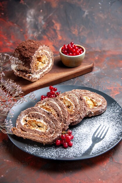 Vista frontal de deliciosos rolos de biscoito com frutas na superfície escura