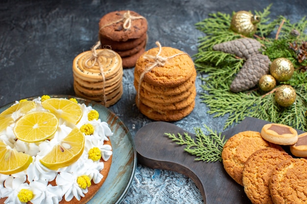 Vista frontal de diferentes deliciosos biscoitos com bolo na superfície claro-escuro