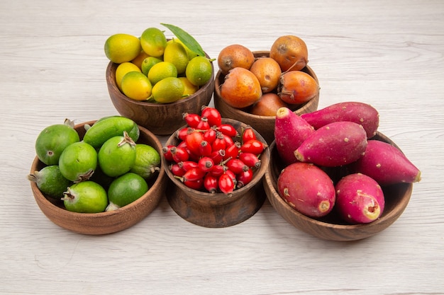 Foto grátis vista frontal de diferentes frutas frescas dentro de pratos em fundo branco cor tropical vida saudável exótica baga madura