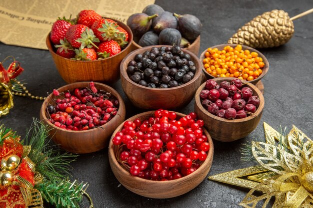 Vista frontal de diferentes frutas frescas dentro de pratos em uma foto de fundo escuro suave com muitas cores de frutas