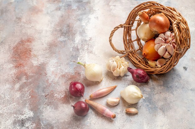 Vista frontal de diferentes ingredientes, cebola e alho dentro da cesta