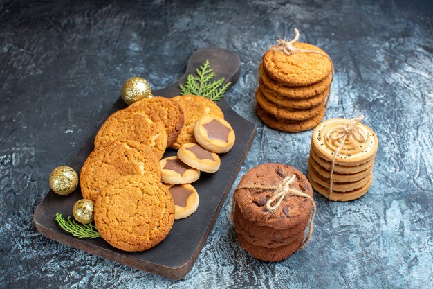 Vista frontal de diferentes saborosos biscoitos em superfície claro-escuro