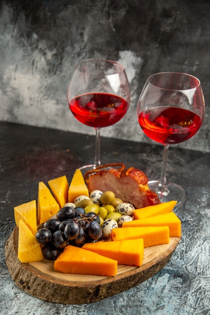 Foto grátis vista frontal de dois copos de vinho tinto seco e lanche em fundo cinza