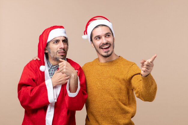 Vista frontal de dois homens de natal olhando para a direita em um fundo bege isolado