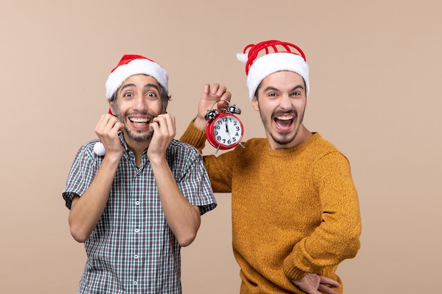 Vista frontal de dois homens exultantes, um segurando um despertador em um fundo bege isolado