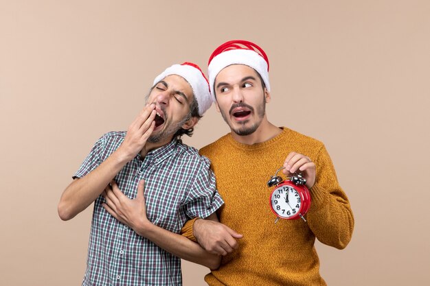 Vista frontal de dois homens sonolentos, um deles bocejando em um fundo bege isolado