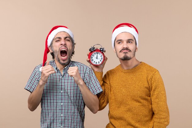 Vista frontal de dois homens, um fazendo gesto vencedor enquanto gritava e o outro segurando um despertador em fundo bege isolado