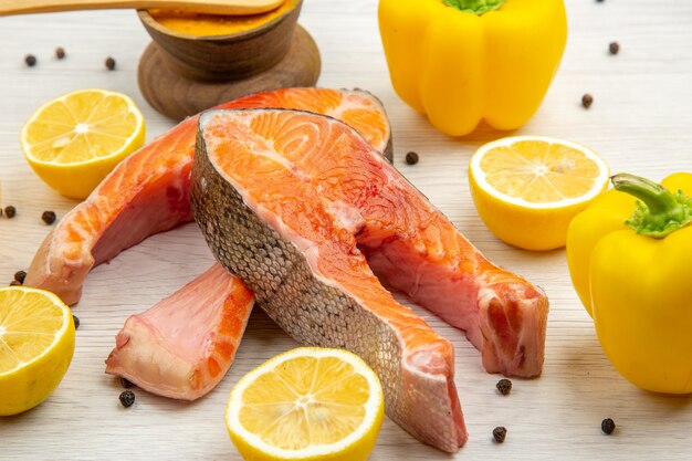 Vista frontal de fatias de carne fresca com rodelas de limão no fundo branco animal peixe costela foto prato comida refeição