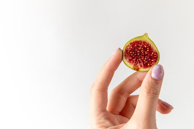 Vista frontal de figo doce fresco em mãos femininas na superfície branca de frutas frescas foto suave