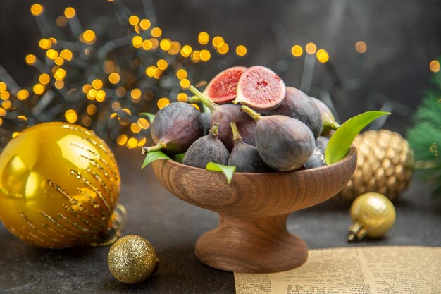 Vista frontal de figos frescos ao redor de brinquedos de natal na mesa escura fruta escura sabor foto de natal