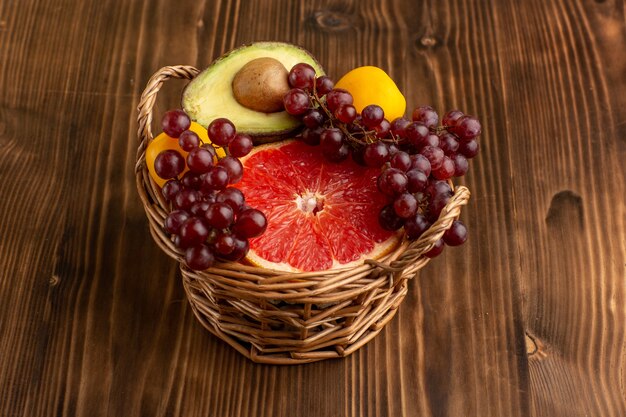 Vista frontal de frutas diferentes dentro da cesta na mesa de madeira marrom