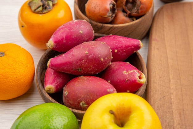 Vista frontal de frutas frescas diferentes dentro de pratos em fundo branco cor madura tropical dieta exótica vida saudável suave