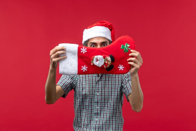 Vista frontal de jovem com meia vermelha de Natal na parede vermelha