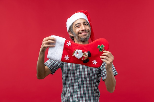 Vista frontal de jovem com meia vermelha de Natal na parede vermelha