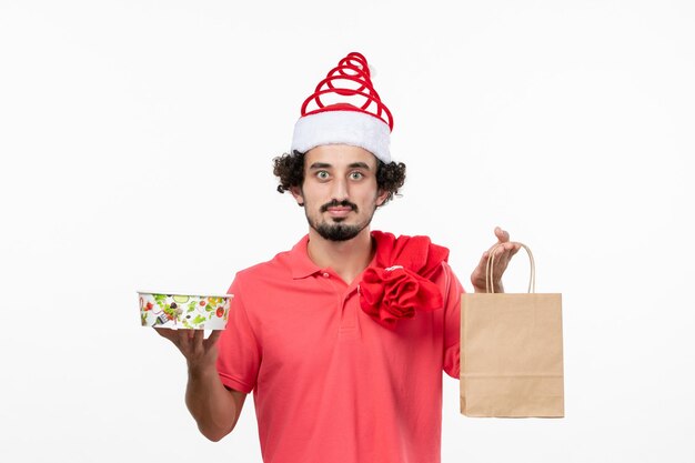 Vista frontal de jovem segurando comida de entrega na parede branca