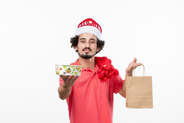 Vista frontal de jovem segurando comida de entrega na parede branca