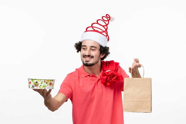 Vista frontal de jovem segurando comida de entrega na parede branca