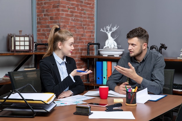 Vista frontal de jovens trabalhadores de escritório discutindo um assunto importante no escritório