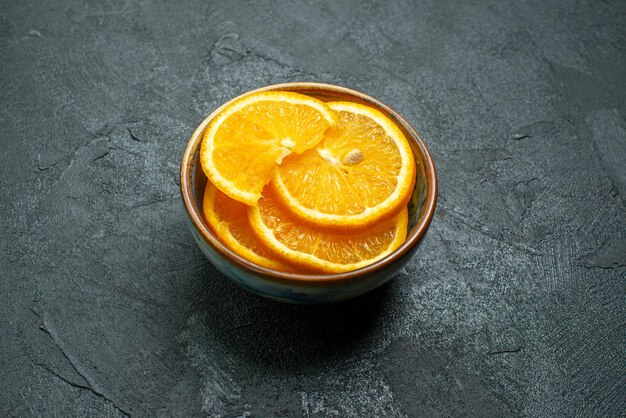 Vista frontal de laranjas frescas fatiadas dentro de um prato em uma superfície escura com suco de frutas tropicais cítricas exóticas