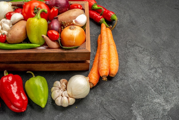 Vista frontal de legumes frescos com pimenta e alho na mesa escura cor de salada madura saúde