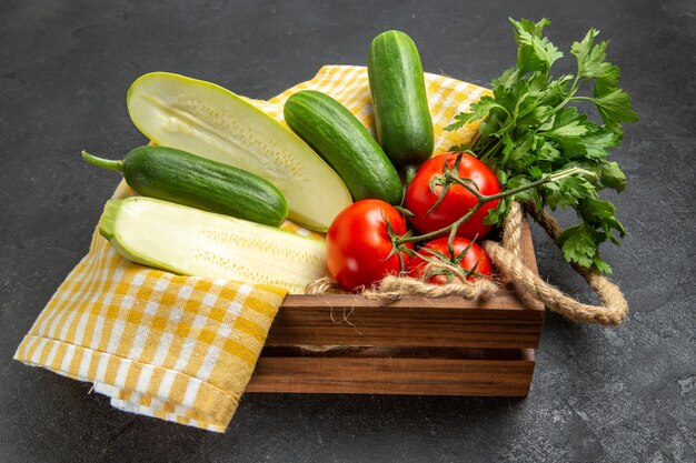 Vista frontal de legumes frescos, tomates, pepinos, abóbora e verduras em um espaço cinza