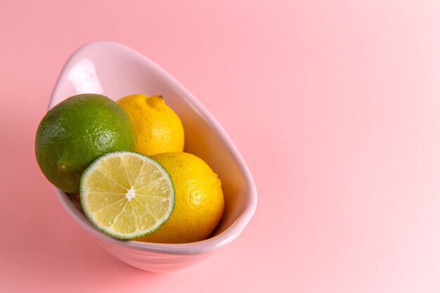 Vista frontal de limão fresco com limão fatiado dentro do prato na parede rosa