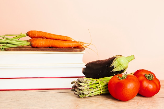 Vista frontal de livros e legumes com fundo liso