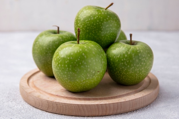 Vista frontal de maçãs verdes em um suporte em um fundo branco