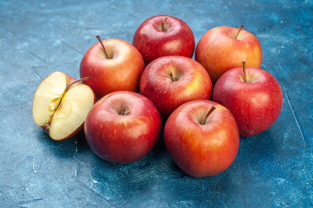 Vista frontal de maçãs vermelhas frescas alinhadas na superfície azul