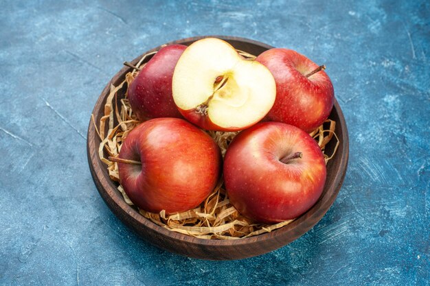 Vista frontal de maçãs vermelhas frescas dentro do prato na superfície azul