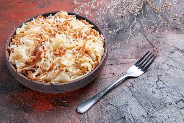 Vista frontal de massa cozida fatiada com arroz em prato de superfície escura farinha de massa