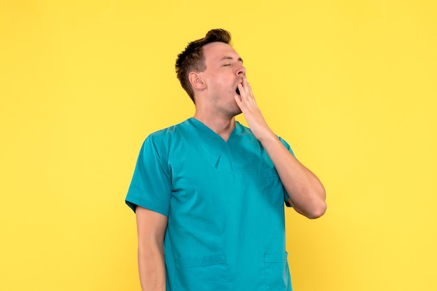 Foto grátis vista frontal de médico bocejando na parede amarela
