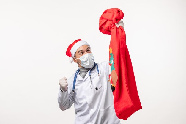 Vista frontal de médico com bolsa de presente na parede branca