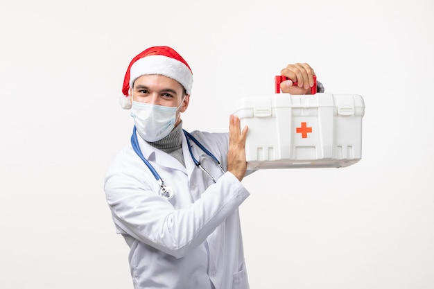 Vista frontal de médico com kit de primeiros socorros na parede branca