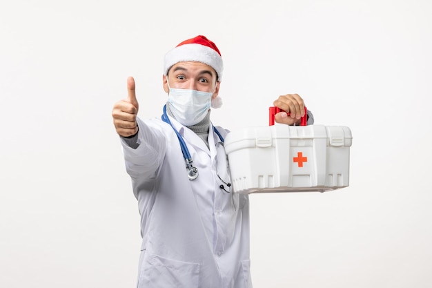 Vista frontal de médico com kit de primeiros socorros na parede branca