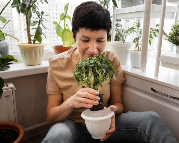 Vista frontal de mulher cheirando plantas de interior