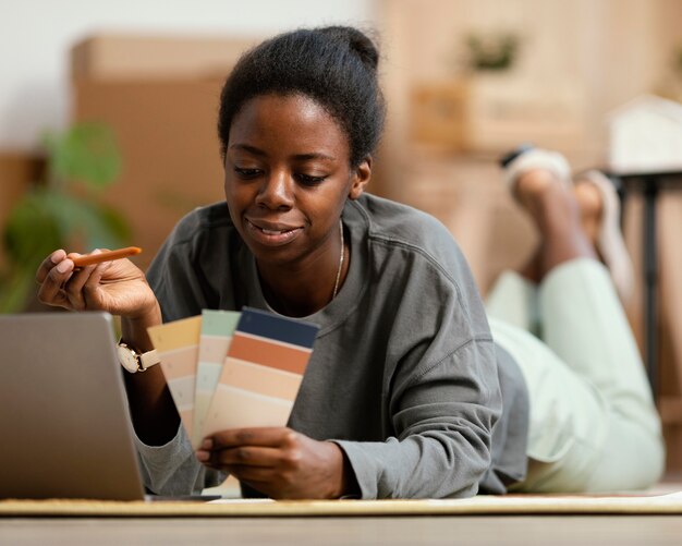 Vista frontal de mulher fazendo planos para redecorar a casa com laptop e paleta de cores