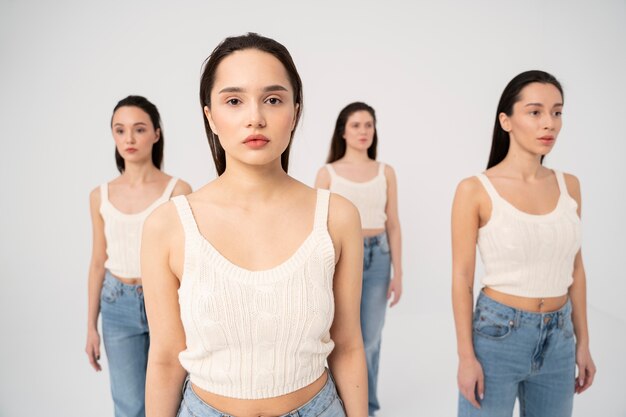 Vista frontal de mulheres em tops e jeans posando em retratos minimalistas