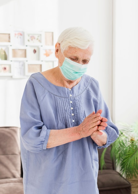 Vista frontal de mulheres mais velhas com máscara médica orando