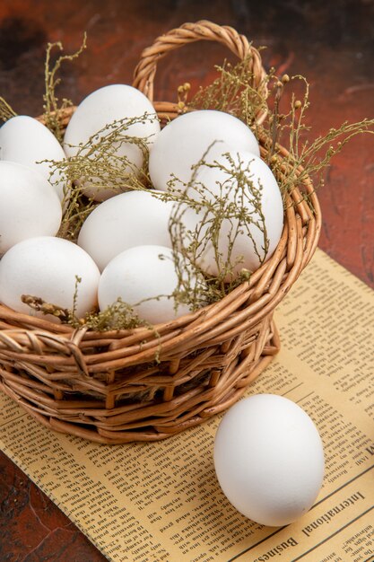 Vista frontal de ovos de galinha dentro da cesta na superfície escura