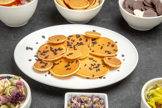 Vista frontal de panquecas deliciosas com biscoitos no escuro