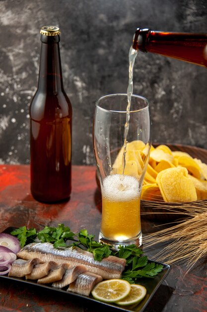 Vista frontal de peixe fresco fatiado com verduras e cerveja no escuro