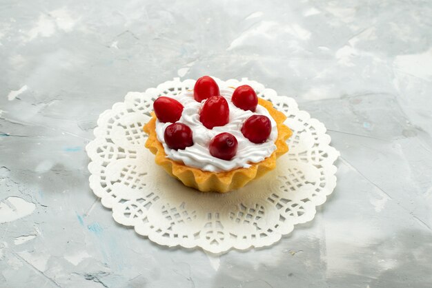 Vista frontal de perto bolo delicioso com creme e frutas vermelhas na superfície clara chá doce